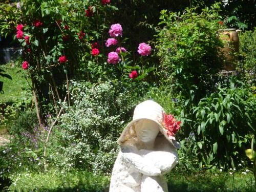 a statue of a girl in a garden with flowers at Le Logis d'Elisa in Cosne-Cours-sur-Loire