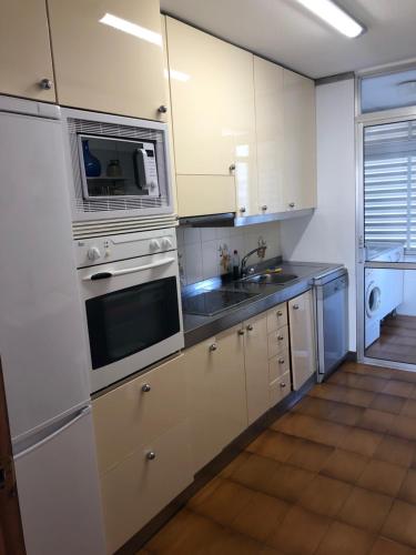 una cocina con armarios blancos y electrodomésticos de acero inoxidable en Face à La Mer, en Calafell