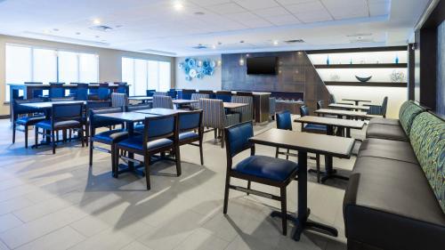 a restaurant with tables and chairs and a television at Holiday Inn Express & Suites Midland Loop 250 by IHG in Midland