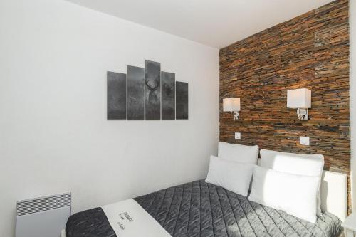 um quarto com uma cama e uma parede de tijolos em SUPERBE T2 CLASSÉ, 34 M2, 3ÈME ÉTAGE, RÉSIDENCE « SÉPIA » AVORIAZ em Avoriaz