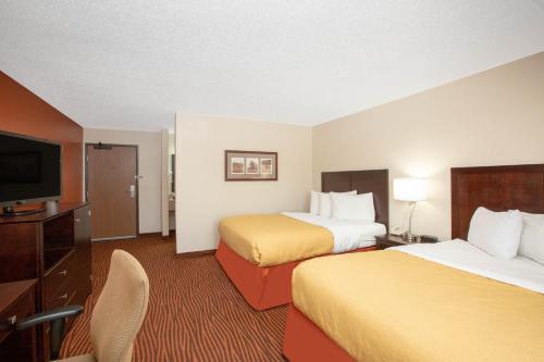 a hotel room with two beds and a flat screen tv at AmericInn by Wyndham Muscatine in Muscatine