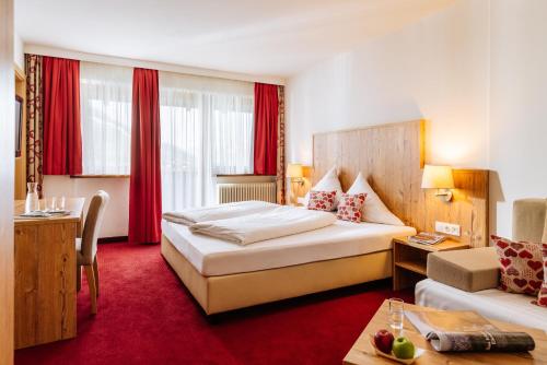 a hotel room with a bed, table, chairs and lamps at Hotel Kögele in Innsbruck