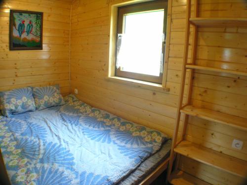 a bed in a log cabin with a window at Mały domek pod lasem in Zakopane
