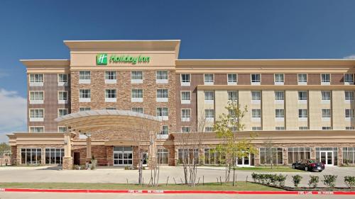 a hotel building with a sign on the front of it at Holiday Inn Garland by IHG in Garland