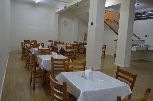 a dining room with white tables and wooden chairs at Colonial Hotel Itatiba in Itatiba