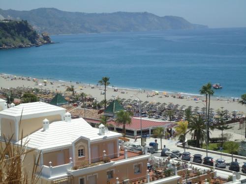 
a beach with a beach house and a large building at Apartamentos Almoraide Suites - Adults Only in Nerja
