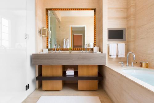 uma casa de banho com um lavatório, uma banheira e uma televisão em Hotel Bel-Air - Dorchester Collection em Los Angeles