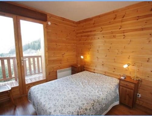 1 dormitorio con cama, paredes y ventanas de madera en Appartement neuf avec terrasse sur Praloup 1600 en Uvernet