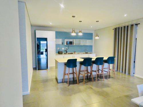 una cocina con una barra con sillas azules. en The Executive - Exclusive Self-Catering Apartments - Ezulwini en Ezulwini