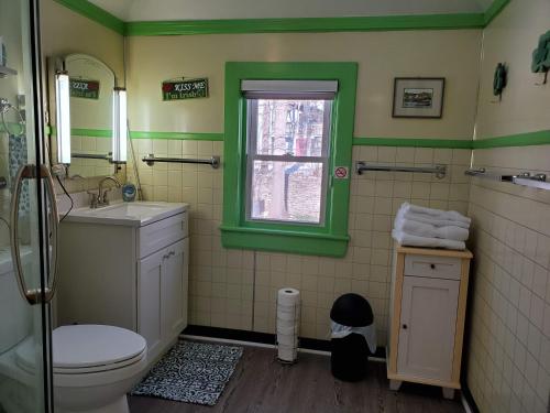 a green bathroom with a toilet and a window at Natalie House in Boston