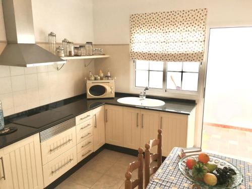 cocina con mesa, fregadero y microondas en Samsara Home, en Caleta de Sebo