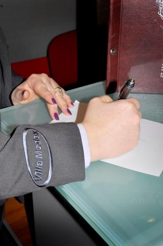 a person in a suit writing on a piece of paper at Guesthouse Villa Modex in Paraćin
