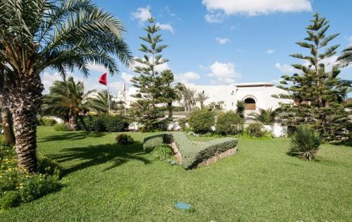 a park with a bench and palm trees and a building at Djerba Resort- Families and Couples Only in Houmt Souk