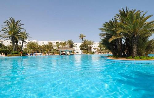 a large swimming pool with palm trees and buildings at Djerba Resort- Families and Couples Only in Houmt Souk