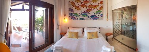 una camera da letto con un letto bianco con cuscini gialli di Geco di Giada Art Suites - Adult Only a Porto Rotondo