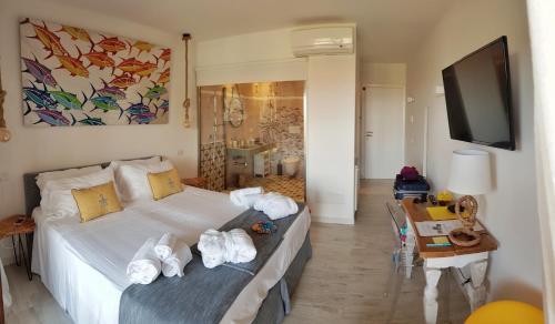 Geco di Giada Art Suites - Adult Only في بورتو روتوندو: غرفة نوم بسرير وتلفزيون وطاولة