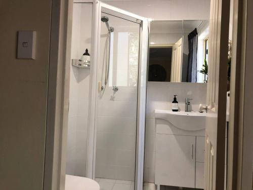a white bathroom with a shower and a sink at Escape to Strathfield for 8 guests in Sydney