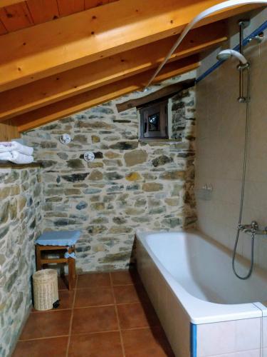 a bathroom with a bath tub in a stone wall at La Forqueta y El Fontanal in Santa María de Ordás