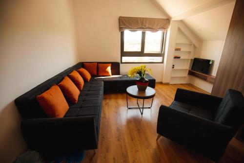 a living room with a black couch and orange pillows at Ngan Hoa - Mille Fleurs 02 in Da Lat