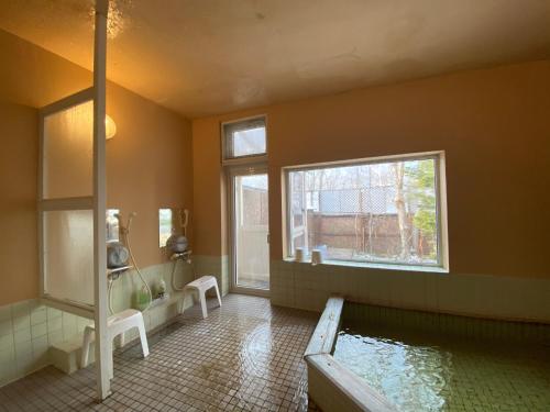 a bathroom with a tub and a pool of water at Forestlodge Subaru in Teshikaga