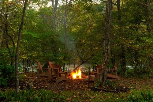 a fire in the woods with chairs around it at Paddler's Lane Retreat in Confluence