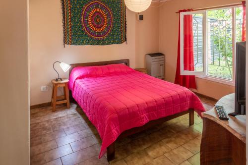 1 dormitorio con cama roja y ventana en casa kenya en El Bolsón