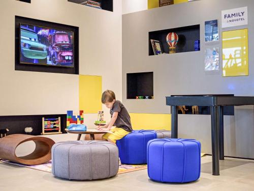 a young boy sitting at a table with luggage at Novotel Sorocaba in Sorocaba