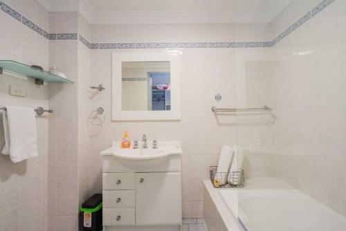 a white bathroom with a sink and a bath tub at Home away from Home Parramatta in Sydney