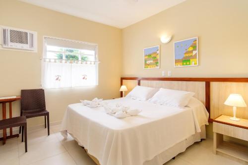 a bedroom with a large white bed and a window at Pousada Don Diego in Ubatuba