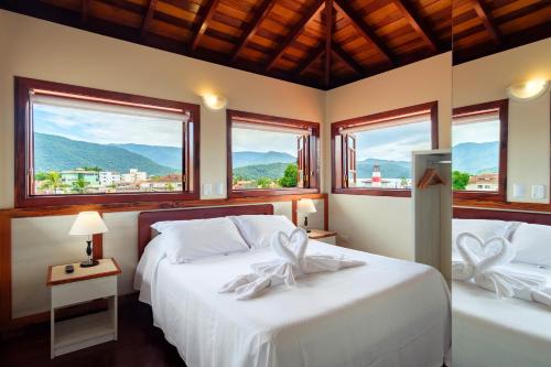 two beds in a room with two windows at Pousada Don Diego in Ubatuba