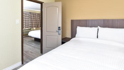 a bedroom with a large white bed and a mirror at Sea Rock Inn - Long Beach in Long Beach