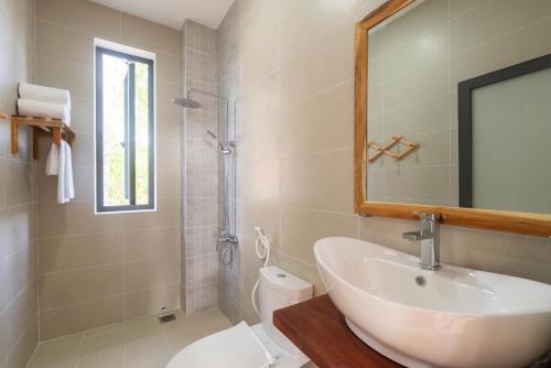 a bathroom with a sink and a toilet and a mirror at Aurora House in Phú Quốc