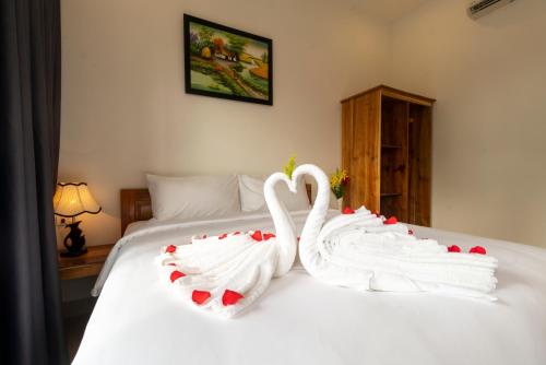 two white swans are sitting on a bed at Aurora House in Phu Quoc