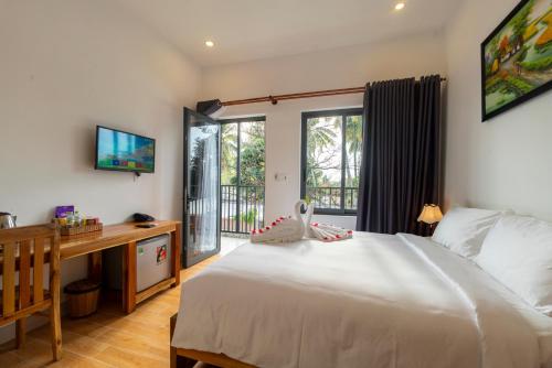 a bedroom with a bed and a desk with a television at Aurora House in Phú Quốc