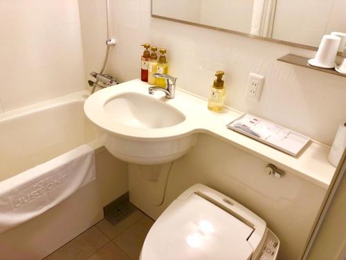 a small bathroom with a toilet and a sink at Hotel Just One Susono in Susono