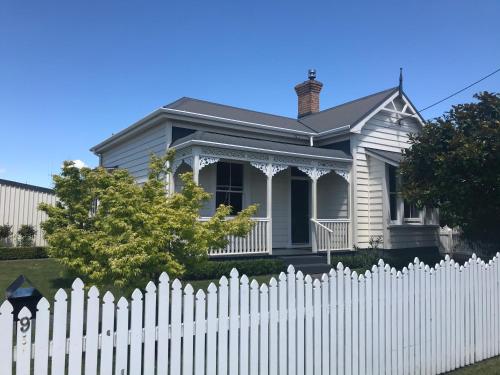 a white picket fence in front of a white house at Bryce Cottage in Cambridge
