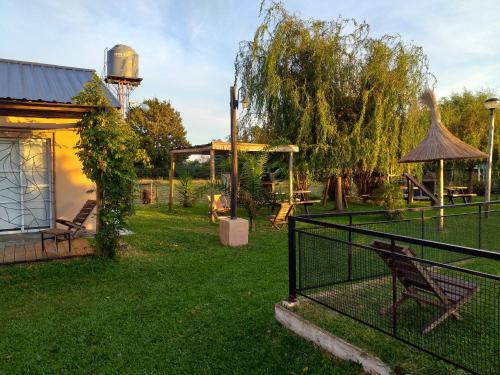 a dog sitting behind a fence in a yard at Aitue Bungalows in Gualeguaychú