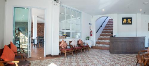 a lobby with a staircase and chairs and a stair case at Sino Mansion in Ranong