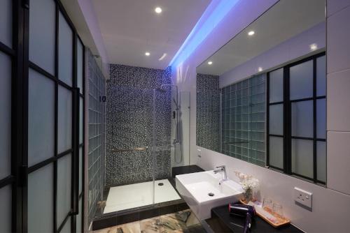 a bathroom with a sink and a shower and a mirror at Macalister Terraces Hotel in George Town