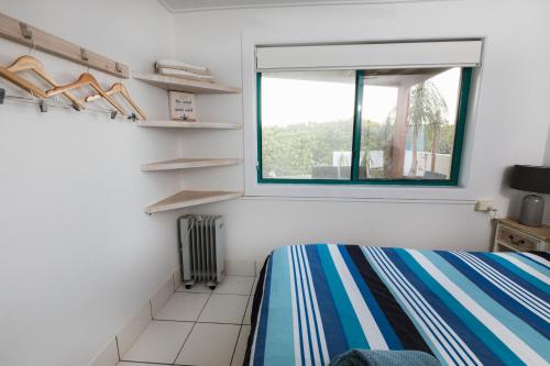 a bedroom with a bed and a window and shelves at White Waves on the Beach in Hastings Point
