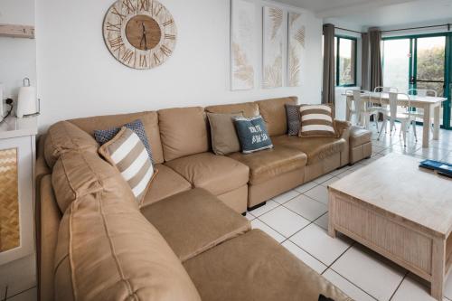 a living room with a brown couch and a table at White Waves on the Beach in Hastings Point