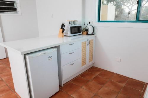 a kitchen with a counter with a microwave and a refrigerator at White Waves on the Beach in Hastings Point