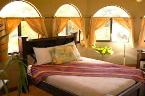 a bedroom with a bed with two windows at Villa Los Aires Costa Rica in Caña Blanca