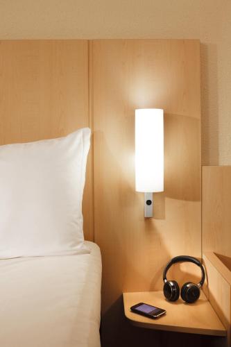 a hotel room with a bed and a lamp and headphones at Hotel Ibis Milano Malpensa in Cardano al Campo