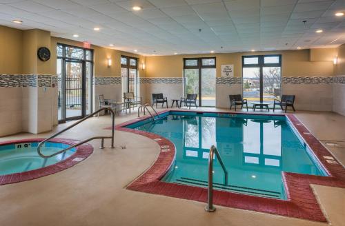 Holiday Inn Express & Suites Laurel Lakes, an IHG Hotel في لاوريل: مسبح في غرفة الفندق مع طاولات وكراسي