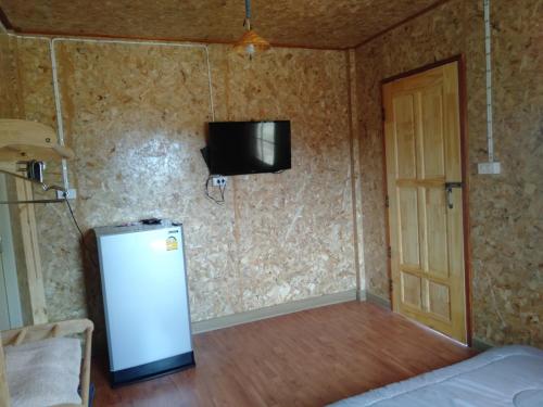 a room with a refrigerator and a tv on the wall at Sleep & fishing Pua in Nan