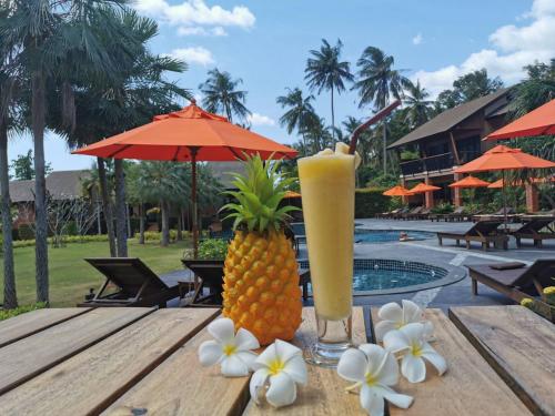 a pineapple drink on a wooden table next to flowers at Aonang Hill Krabi-SHA Extra Plus in Ao Nang Beach
