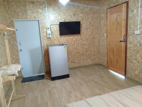 a room with a refrigerator and a tv on the wall at Sleep & fishing Pua in Nan