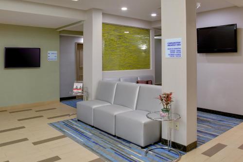 a waiting room with a white couch and a tv at Holiday Inn Express Hotel & Suites Meadowlands Area by IHG in Carlstadt