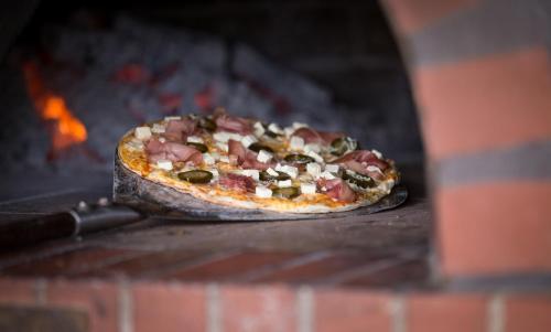 a pizza is cooking in a brick oven at De Zeekoe Guest Farm in Oudtshoorn